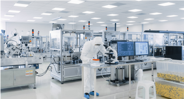 A man in a white lab coat is focused on his work at a computer, representing Pharma Access Capabilities.